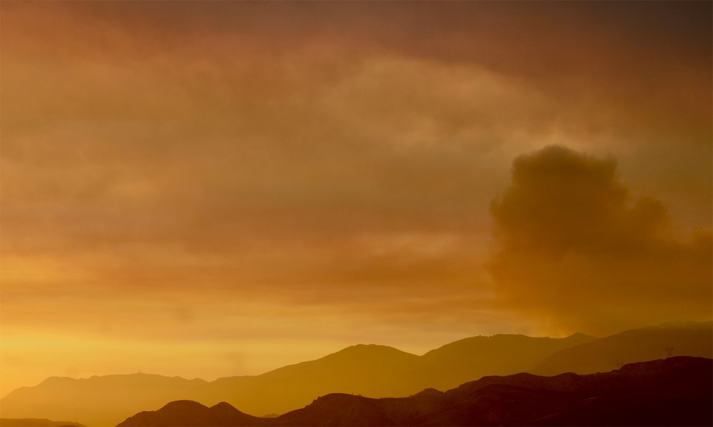 Hills with smoke and orange sky